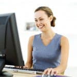 Young Woman Sitting in Front of a Computer and Laughing