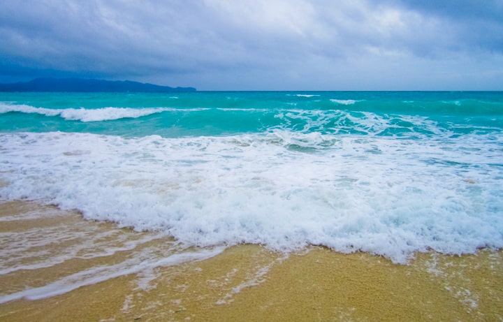 A little wave crashing against the beach, blue and white foamy surf.