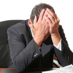 A stress man face his palm in agony.