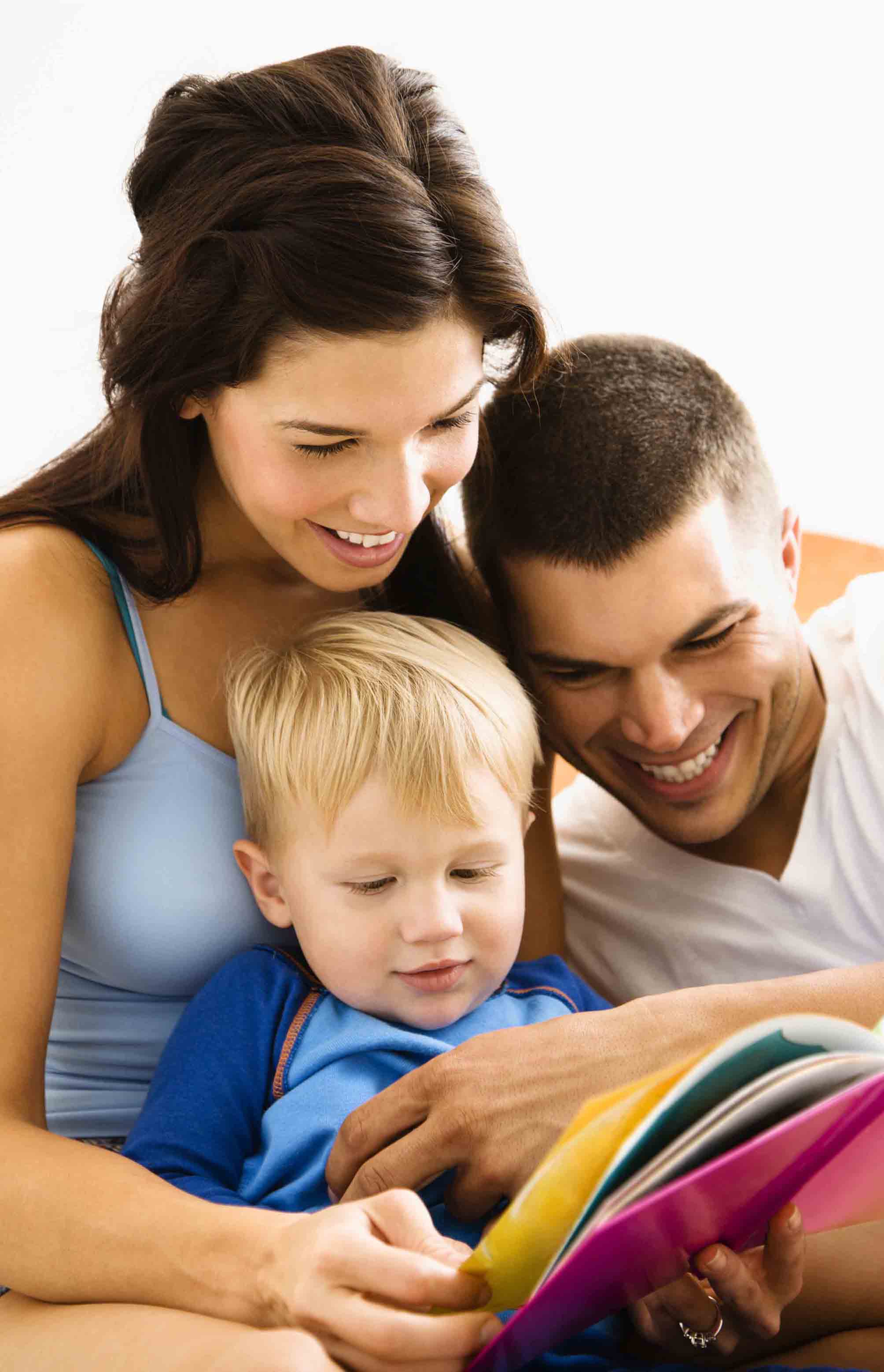 Caucasian parents and toddler son reading book.