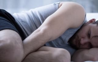 Depressed man lying on bed.