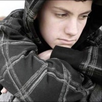 A depressed young man sitting alone.