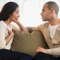 A couple arguing on a sofa.